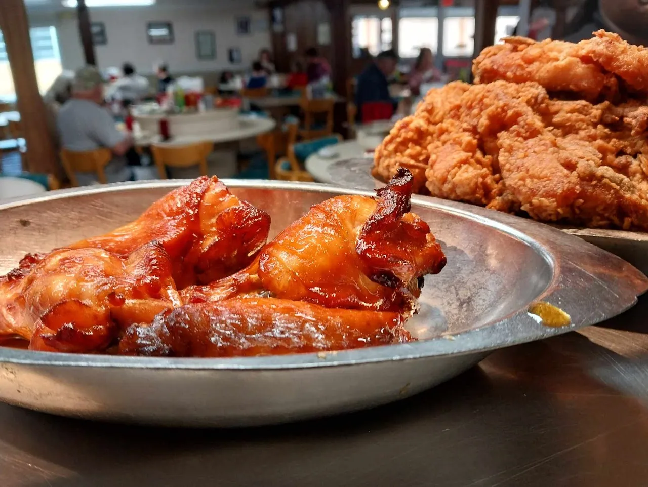 Golden fried chicken and BBQ in Bea's metal serving dishes, with the Chattanooga dining room behind